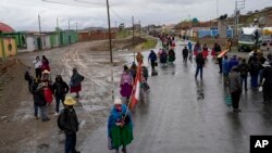 Residentes caminan a lo largo de una barricada colocada por manifestantes que piden la renuncia de la presidenta Dina Boluarte y la disolución del Congreso, en Acora, sur de Perú, el domingo 2 de enero de 2019.