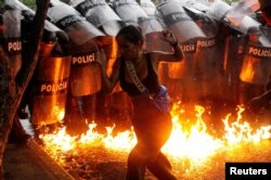 Demonstrantkinja reaguje u trenutku kada molotovljevi kokteli padaju na tlo ispred snaga bezbednosti tokom protesta protiv izbornih rezultata u Puerto La Kruzu, Venecuela, 29. jula 2024.