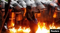 Seorang demonstran bereaksi saat bom molotov dijatuhkan di depan pasukan keamanan selama protes hasil pemilu di Puerto La Cruz, Venezuela, pada 29 Juli 2024. (Foto: REUTERS/Samir Aponte)