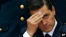 FILE - In this Sept. 7, 2017 file photo, Mexico's President Enrique Pena Nieto wipes sweat from his forehead during the International Financial Inclusion Forum at the National Palace in Mexico City.