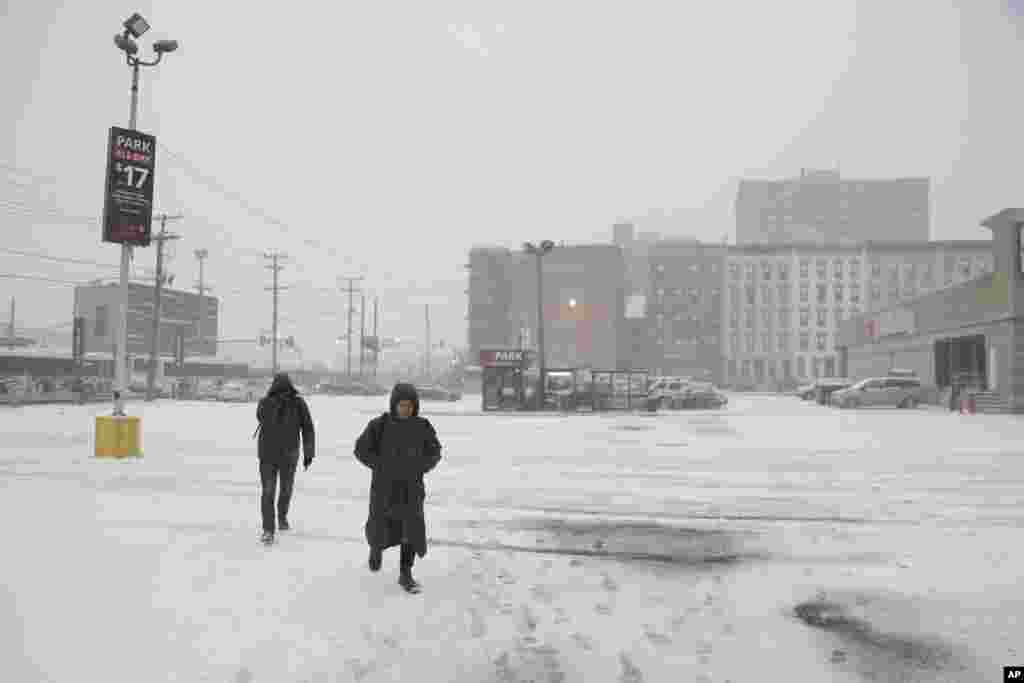 Deux personnes marchent dans un parking presque vide à Hoboken, N.J., le jeudi 4 janvier 2018.