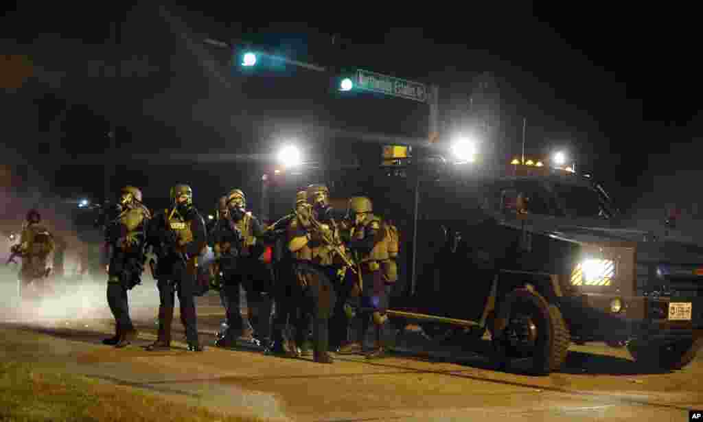 Police take up positions after being shot at Monday, Aug. 18, 2014, in Ferguson. Police have used riot gear and tear gas and Gov. Jay Nixon ordered the National Guard to help restore order Monday. (AP Photo/Jeff Roberson)