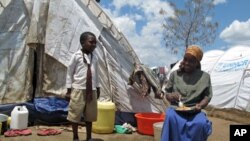 A boy talks to his mother, both internally-displaced persons, as she has lunch outside their temporary holding ground in Nakuru, Kenya, April 2008 (file photo)