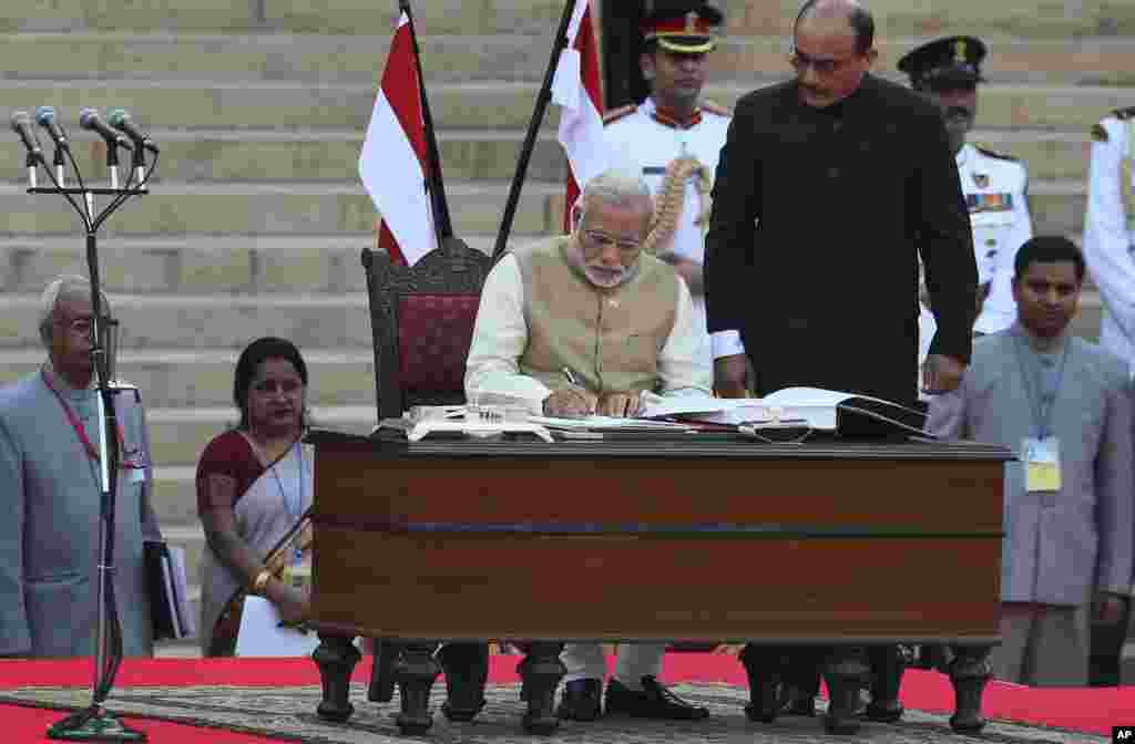 India's new prime minister Narendra Modi signs after taking the oath of office at the presidential palace in New Delhi, May 26, 2014.