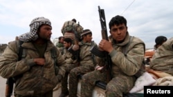 Kurdish People's Protection Units (YPG) fighters carry their weapons while riding on the back of a pick-up truck in Qamishli, Syria, March 11, 2016. 