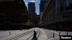 A pedestrian wearing a protective face mask crosses tram lines in the city center during a lockdown to curb the spread of COVID-19 in Sydney, Australia, 24, 2021.