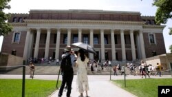 FILE - People stop to photograph Widener Library on the campus of Harvard University in Cambridge, Mass., July 16, 2019.