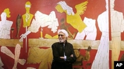 Indian artist Maqbool Fida Husain stands against one of his paintings titled 'Last Supper' at the opening of his exhibition '...and not only 88 of Hussain' at the National Art Gallery in Mumbai.