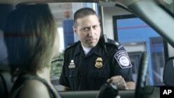 FILE - U.S. Customs and Border Protection officer Kevin Corsaro speaks with an unidentified motorist entering the United States from Canada at the border in Buffalo, N.Y.