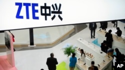 FILE - People are seen gathered at a ZTE company booth at the Mobile World Congress in Barcelona, Spain, Feb. 26, 2014.
