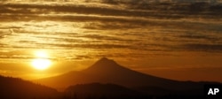 FILE - The sun rises over Mount Hood in the aftermath of the largest solar storm in years, over Portland, Oregon, on March 8, 2012.