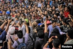 Twp men convicted of gay sex, center, are surrounded as Shariah law officials escort them to a mosque to be publicly caned in Banda Aceh, Aceh province, Indonesia, May 23, 2017.