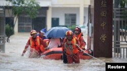 Petugas SAR yang mengevakuasi warga dengan perahu karet terjebak arus banjir di tengah hujan deras di Kabupaten Duchang, Provinsi Jiangxi, China, 8 Juli 2020.