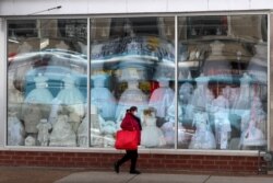 A woman wearing a protective mask walks past a closed children's clothing store in the Hispanic, Little Village in Chicago on April 15, 2020.