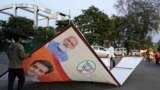 Petugas membereskan spanduk yang menampilkan gambar Perdana Menteri India Narendra Modi di Lucknow, Uttar Pradesh, pada 16 Maret 2024. (Foto: AP/Rajesh Kumar Singh)