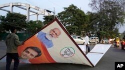 Petugas membereskan spanduk yang menampilkan gambar Perdana Menteri India Narendra Modi di Lucknow, Uttar Pradesh, pada 16 Maret 2024. (Foto: AP/Rajesh Kumar Singh)