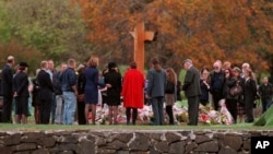 FILE - Families and friends are seen gathered around a memorial at a service in memory of 35 people killed, on the first anniversary of a rampage by a lone gunman in Port Arthur, Tasmania, Australia, April 28, 1997.