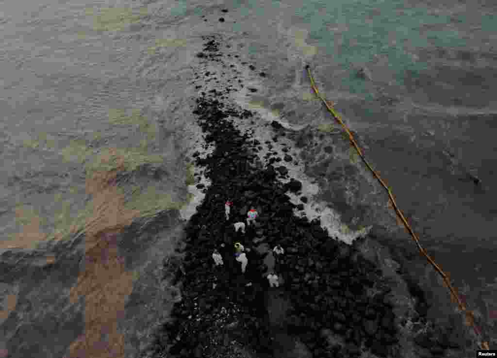 Workers clean the beach near Repsol&#39;s La Pampilla refinery after the recent oil spill that has caused an ecological disaster on the coast of Lima, in Ventanilla, Peru, Jan. 29, 2022.