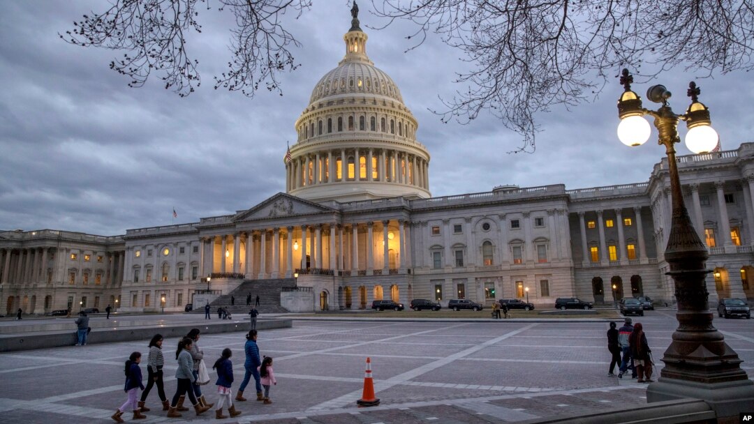 FILE - People walk by the U.S. Capitol in Washington, Jan. 21, 2018, as lawmakers prepare to vote on a spending bill that would fund U.S. government operations for the remainder of the current fiscal year which ends Sept. 30.