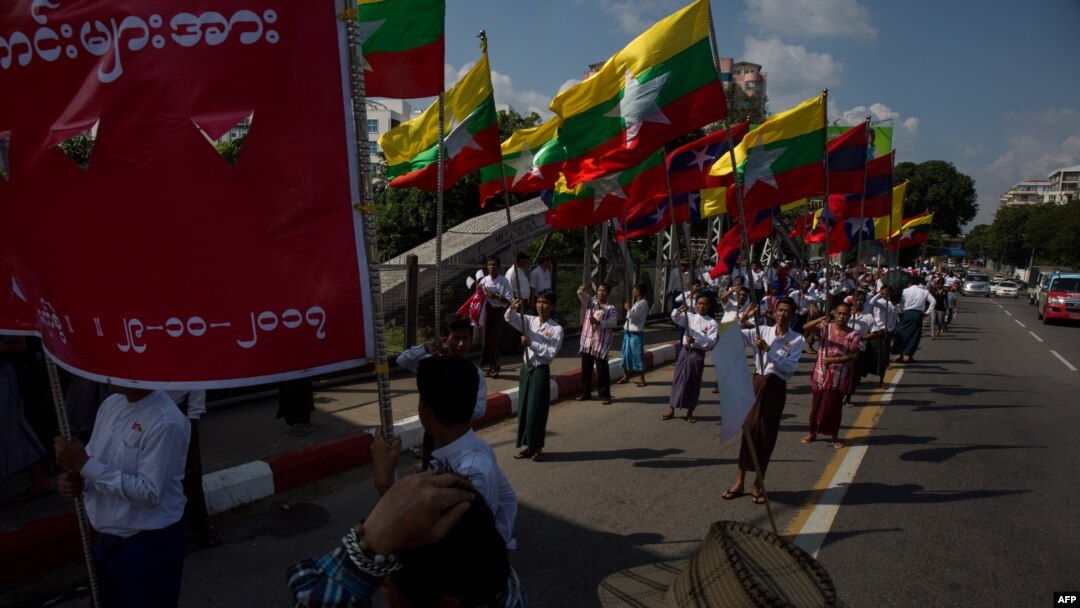Men carry Myanmar national flags as they march in a show of support for the country's military and civil servants, in Yangon, Myanmar, Oct. 29, 2017.