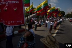 Men carry Myanmar national flags as they march in a show of support for the country's military and civil servants, in Yangon, Myanmar, Oct. 29, 2017.