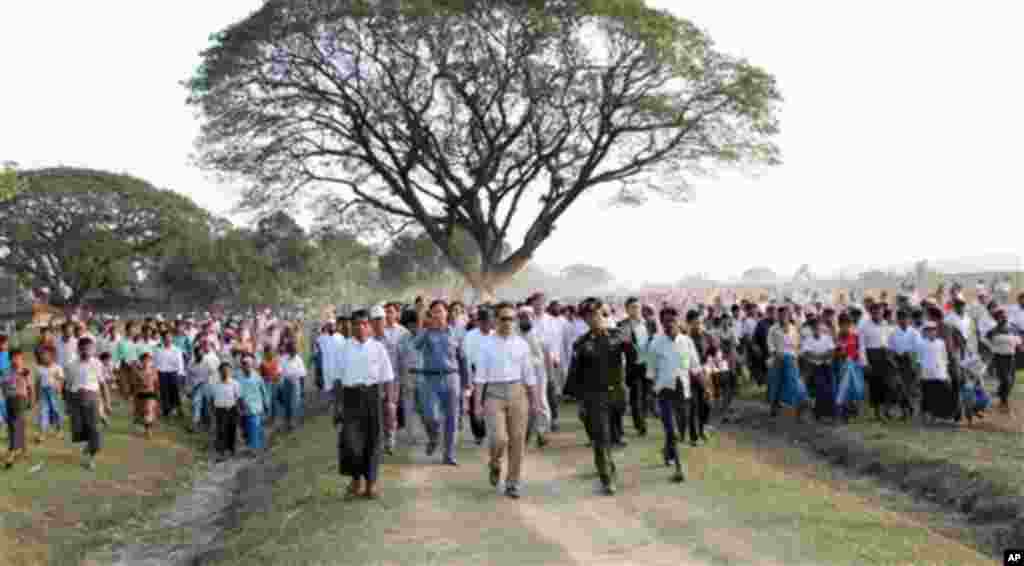 Hundreds of Muslim refugees follow Indonesian Foreign Minister Marty Natalegawa, front row second left, being escorted by Myanmar Border Affair Minister Lt. General Thein Htay, front row second right, as he visits a refugee camp in Maungtaw, Rakhine State