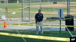 A police office stands watch behind police tape near strewn baseballs on a field in Alexandria, Va., Wednesday, June 14, 2017, after a multiple shooting involving House Majority Whip Steve Scalise of Louisiana. 