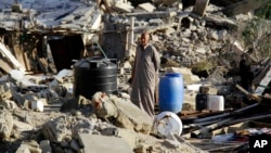 FILE - A man stands in the rubble off a home demolished by security forces on the on the Egyptian side of border town of Rafah, northeast of Cairo, Egypt, Nov. 6, 2014.