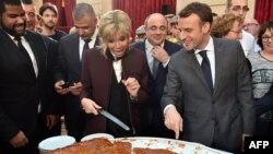 French President Emmanuel Macron and his wife Brigitte cut slices of a traditional epiphany cake during a ceremony at the Elysee palace, Paris, Jan. 12, 2018.