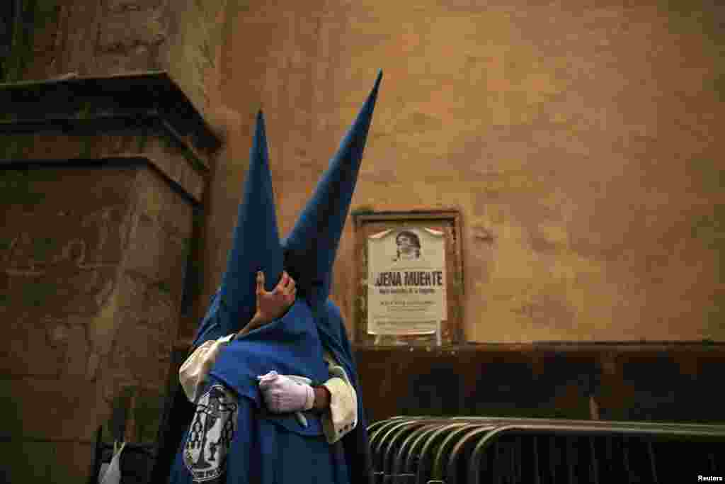 Penitents of &quot;San Esteban&quot; brotherhood embrace next to a poster for a church event which reads &quot;Good death&quot; during Holy Week in the Andalusian capital of Seville, southern Spain, Mar. 26, 2013. Hundreds of Easter processions take place around the clock in Spain during Holy Week, drawing thousands of visitors.