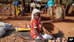 In this Wednesday, May 13, 2020, photo, a child sits on the ground selling onions at a market stall in Tougan, Burkina Faso. 