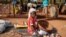 In this Wednesday, May 13, 2020, photo, a child sits on the ground selling onions at a market stall in Tougan, Burkina Faso. 
