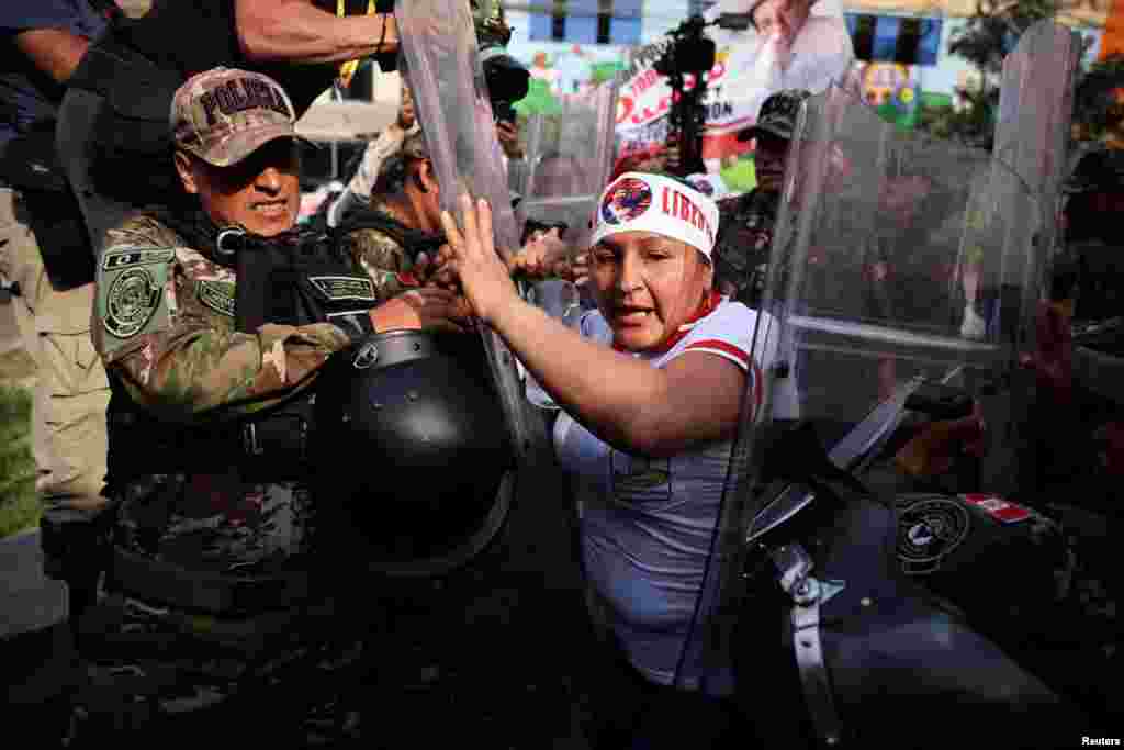 A demonstrator clashes with law enforcement officers as supporters of Peru&#39;s former President Pedro Castillo protest outside the penitentiary center where he is held, on the day of the beginning of his oral trial on charges of rebellion and other offenses against the state, in Lima.