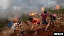 Residents work to prevent a wildfire from spreading to their homes in Vina del Mar, Chile, March 12, 2017. 