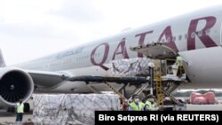 Pekerja mengenakan masker pelindung menurunkan Moderna hasil kerjasama internasional Indonesia-Amerika Serikat melalui fasilitas multilateral COVAX, di terminal kargo Soekarno Hatta International, 11 Juli 2021. (Foto: Courtesy Biro Pers via Reuters)