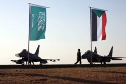 Personel militer berjalan melewati bendera Arab Saudi dan Sudan ketika Presiden Sudan Omar Ahmed al-Bashir menghadiri latihan militer bersama Angkatan Udara Saudi dan Angkatan Udara Sudan di Bandara Merowe di Merowe, Negara Bagian Utara, Sudan 9 April 2017. (Foto: dok).