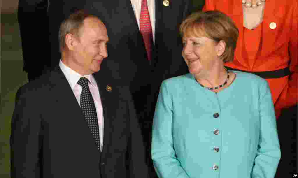 Presiden Rusia Vladimir Putin (kiri) berbicara dengan Kanselir Jerman Angela Merkel selama sesi foto di Hotel Xizi pada KTT G20 di Hangzhou, provinsi Zhejiang, China (4/9).