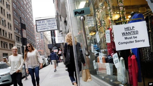 FILE - A "Help Wanted" sign hangs in a store window in New York City, Oct. 1, 2015.