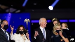 President-elect Joe Biden, his wife Jill Biden, and members of the Biden family, along with Vice President-elect Kamala Harris, her husband Doug Emhoff stand on stage Saturday, Nov. 7, 2020, in Wilmington, Del. (AP Photo/Andrew Harnik)