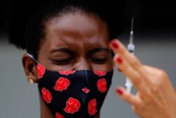 A woman reacts to seeing a syringe of the Sinovac vaccine for COVID-19 as health workers vaccinate residents in the Kalunga Vao de Almas quilombo on the outskirts of Cavalcante, Goias state, Brazil, March 16, 2021.