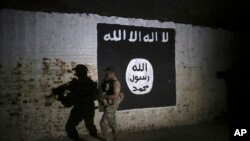 FILE - An Iraqi soldier inspects a recently-discovered train tunnel, adorned with an Islamic State group flag, that belonged to the former Baghdad to Mosul line, that was turned into a training camp for IS fighters, in western Mosul, Iraq, March 1, 2017.