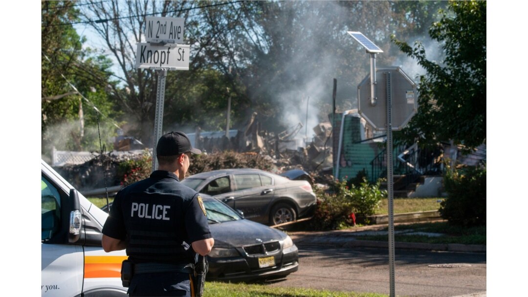 Seorang petugas polisi menjaga sisa-sisa rumah yang meledak, kemungkinan karena masalah saluran gas yang disebabkan oleh banjir parah dari Badai Tropis Ida, di Manville, New Jersey, 3 September 2021. (Foto: AP)