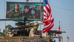 A U.S. armored vehicle drives past a billboard for the Syrian Kurdish Women's Protection Units (YPJ) during a patrol of the Syrian northeastern town of Qahtaniyah at the border with Turkey, October 31, 2019.