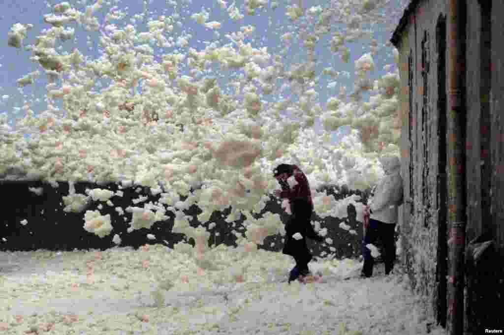 A family is caught in blowing sea foam on the Brittany coast after storm Eleanor hit Saint-Guenole in western France.