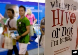 Para peserta berjalan melewati poster pada Kongres Internasional AIDS ke-9 di Nusa Dua, Bali, 10 Agustus 2009. (Foto: AP)