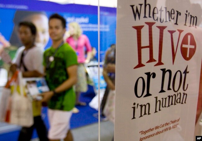 Para peserta berjalan melewati poster pada Kongres Internasional AIDS ke-9 di Nusa Dua, Bali, 10 Agustus 2009. (Foto: AP)
