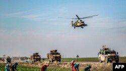 A Russian Mil Mi-17 military helicopter flies over a joint Russian-Turkish military patrol convoy in the countryside near Darbasiyah along the border with Turkey in Syria&#39;s northeastern Hasakah province.