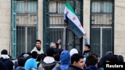 A teacher hoists the flag adopted by the new Syrian rulers at a school in the early morning, following an announcement of the reopening of schools by the authorities, after the ousting of Syria’s Bashar al-Assad, in Damascus, Dec. 15, 2024. 