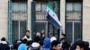 A teacher hoists the flag adopted by the new Syrian rulers at a school in the early morning, following an announcement of the reopening of schools by the authorities, after the ousting of Syria’s Bashar al-Assad, in Damascus, Dec. 15, 2024. 