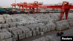 FILE - Workers ride through an aluminum ingots depot in Wuxi, Jiangsu province, China, Sept. 26, 2012. On Friday, China warned of a "huge impact" on trade if the U.S. places tariffs on steel and aluminum.